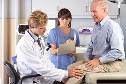 Photo of two medical professionals examining a man's knee.