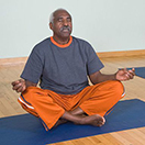 A man sitting with his eyes closed meditating.