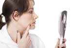 Woman checking face in mirror