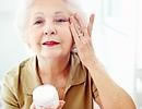 elderly woman rubbing lotion on her face